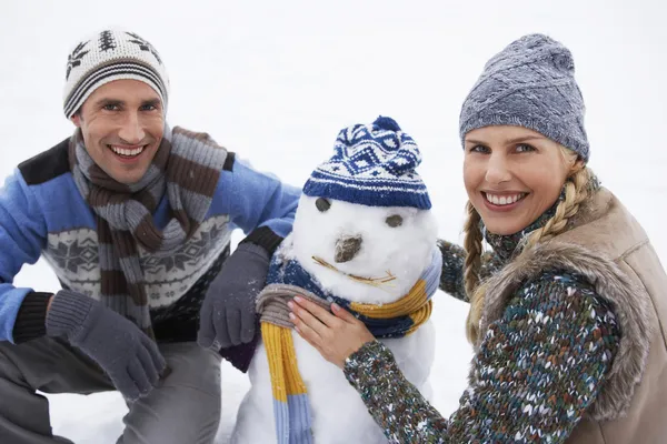 Couple dressing bonhomme de neige — Photo