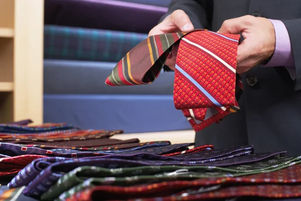 Businessman selecting ties in clothes store — Stock Photo, Image