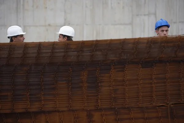 Construction workers behind a stack of rebar — Stock Photo, Image