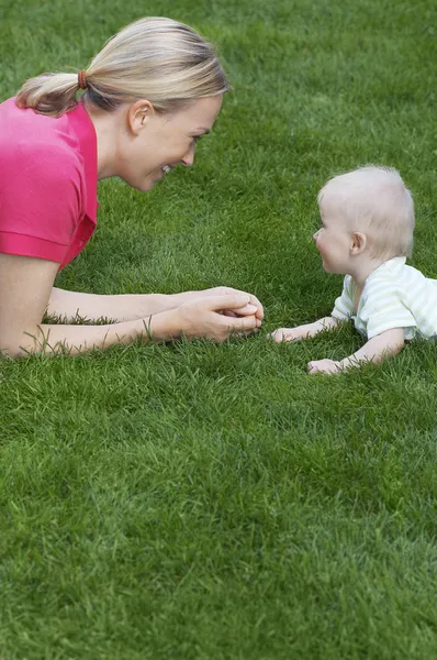 Anne ve çocuk çim üzerinde yalan — Stok fotoğraf