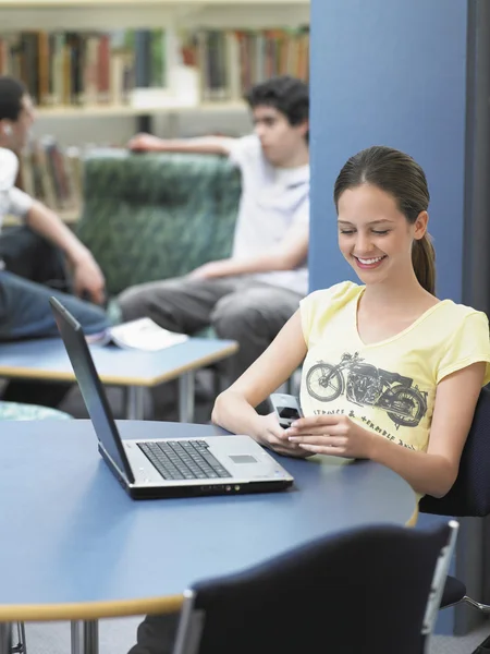 Girl messaging in library — Stock Photo, Image