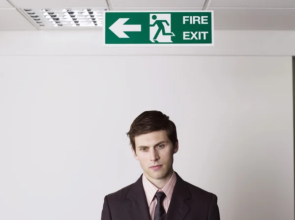 Businessman standing under exit sign — Stock Photo, Image