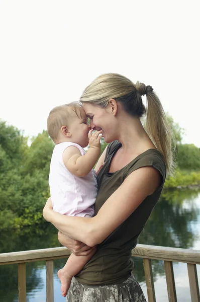 Mother holding daughter by lake — Stock Photo, Image