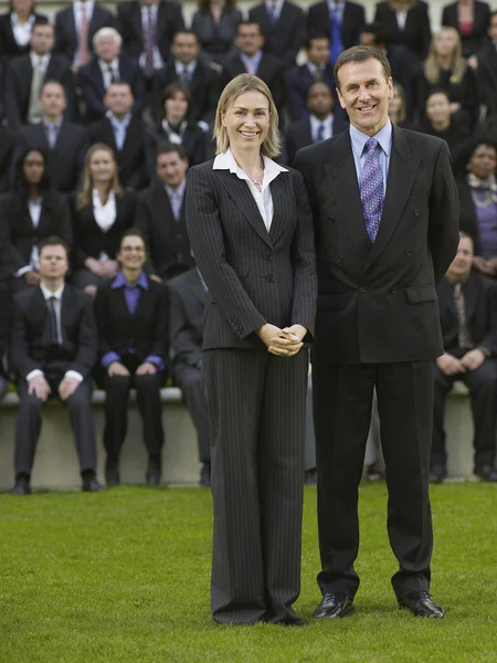 Business couple standing in front of people — Stock Photo, Image