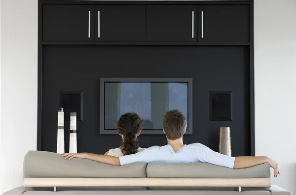 Couple in front of flat screen television — Stock Photo, Image