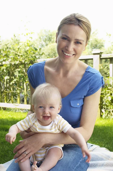 Mère et fils assis sur le tapis dans le jardin — Photo