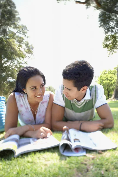 Paar liest Zeitschriften im Gras — Stockfoto