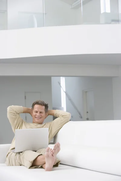 Homem com laptop no sofá — Fotografia de Stock