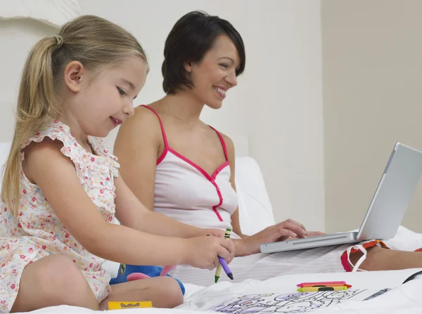 Mother and daughter drawing and using laptop — Stock Photo, Image