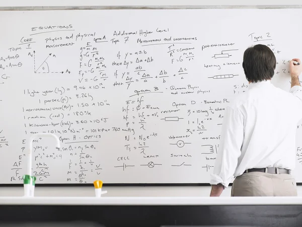 Teacher writing on whiteboard Stock Image