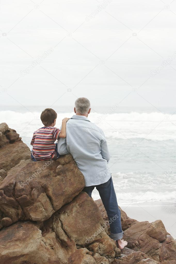 Father and son sitting on rock