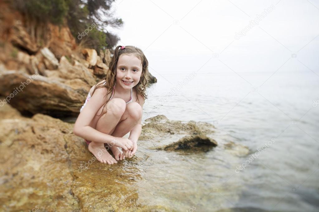 Girl squatting on rock