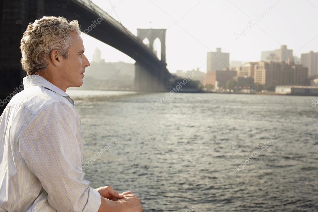 Man looking at river by Brooklyn Bridge