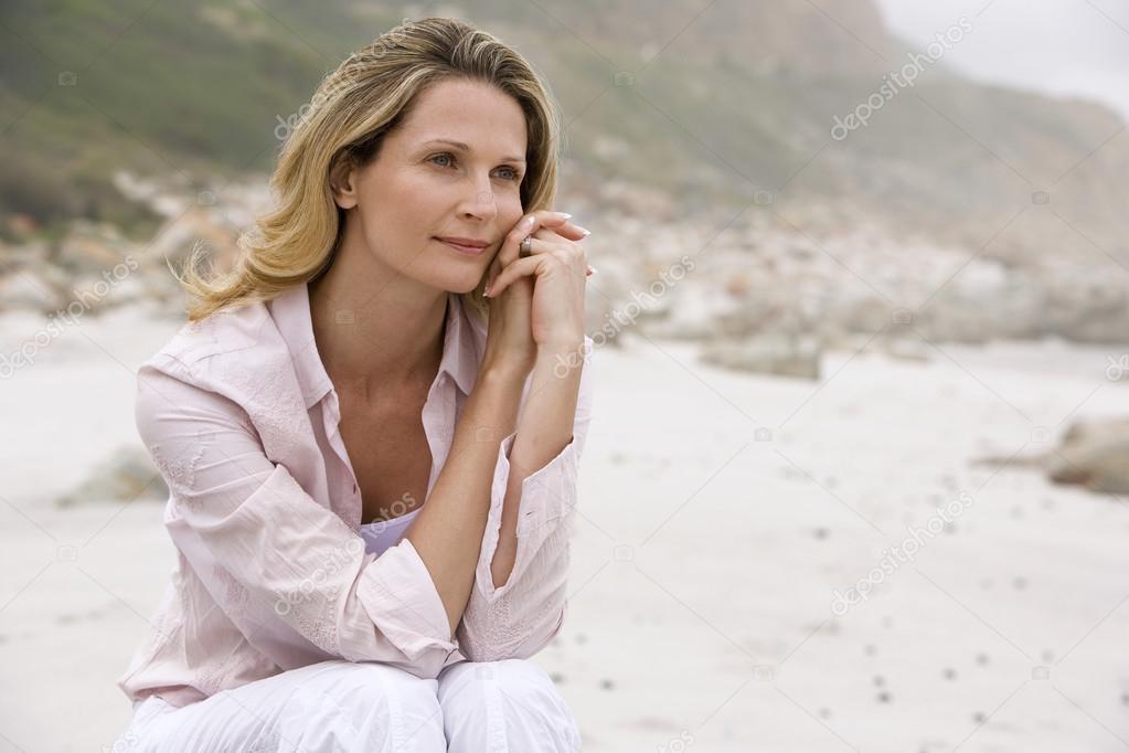 Pensive woman sitting on beach