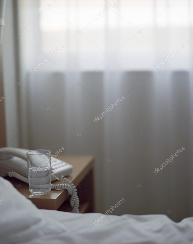 Glass of Water on Nightstand in Hotel Room