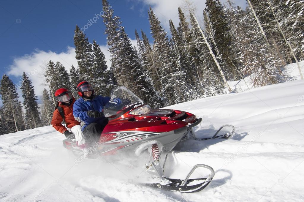Couple driving snowmobile