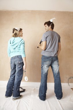 Couple standing holding paint rollers clipart