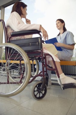 Hemşire hasta tekerlekli sandalyede konuşuyor