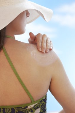 Woman applying sunscreen clipart