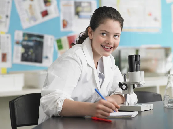 Kvinnliga gymnasiestudent med Mikroskop — Stockfoto