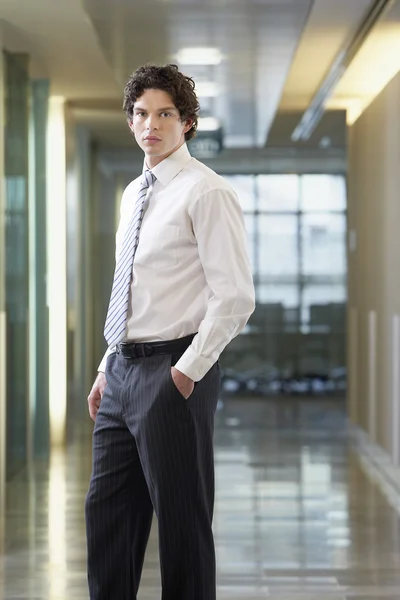Бизнесмен, стоящий в офисном коридоре — стоковое фото