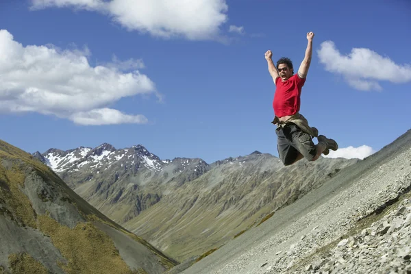 Uomo saltando giù pendio roccioso — Foto Stock