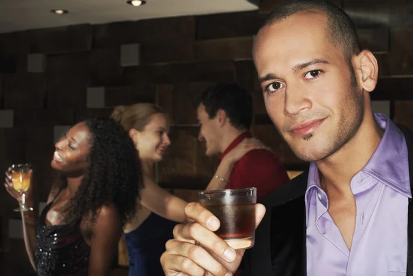 Young man holding drink in bar — Stock Photo, Image