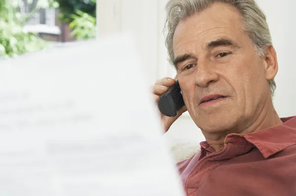 Man using cell phone looking at bill — Stock Photo, Image