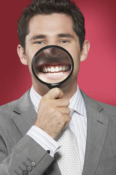 Man holding magnifying glass to smiling — Stock Photo, Image