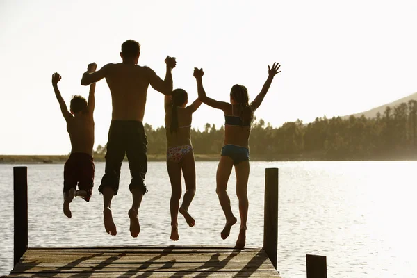 Padre e hijos saltando de un muelle — Foto de Stock