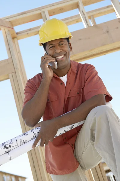 Architect with blueprints using cellphone — Stock Photo, Image
