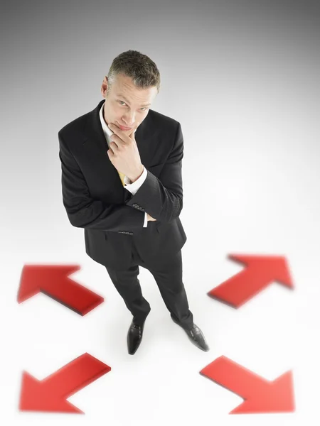 Man in suit in centre of four arrows — Stock Photo, Image