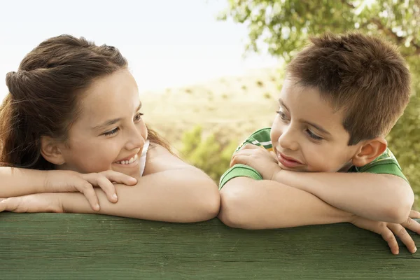 Niño y niña apoyados contra barandilla — Foto de Stock