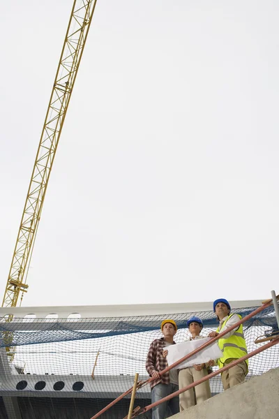 Equipa de construção examinando planos de construção — Fotografia de Stock