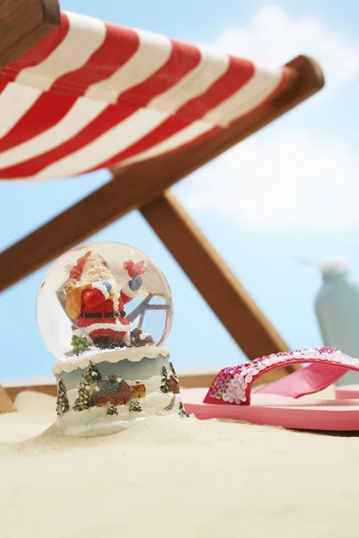 Santa sneeuwbol onder strandstoel — Stockfoto
