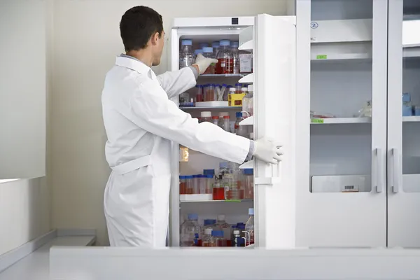 Cientista selecionando o frasco da geladeira — Fotografia de Stock