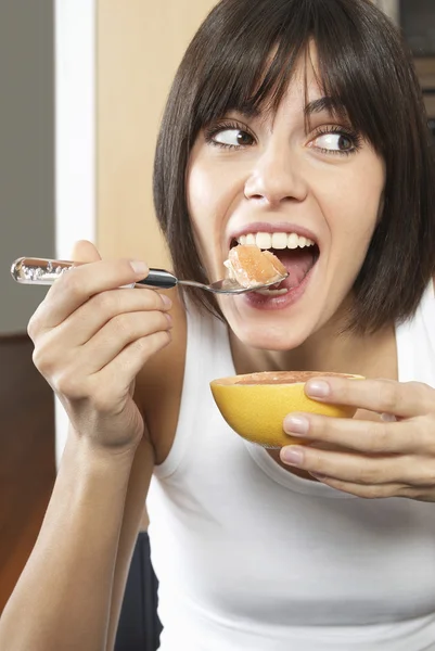 Vrouw eten grapefruit — Stockfoto