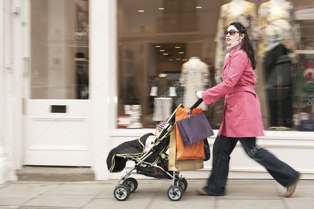 Mother pushing stroller by shop