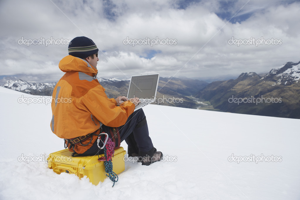 Hiker using laptop on mountain