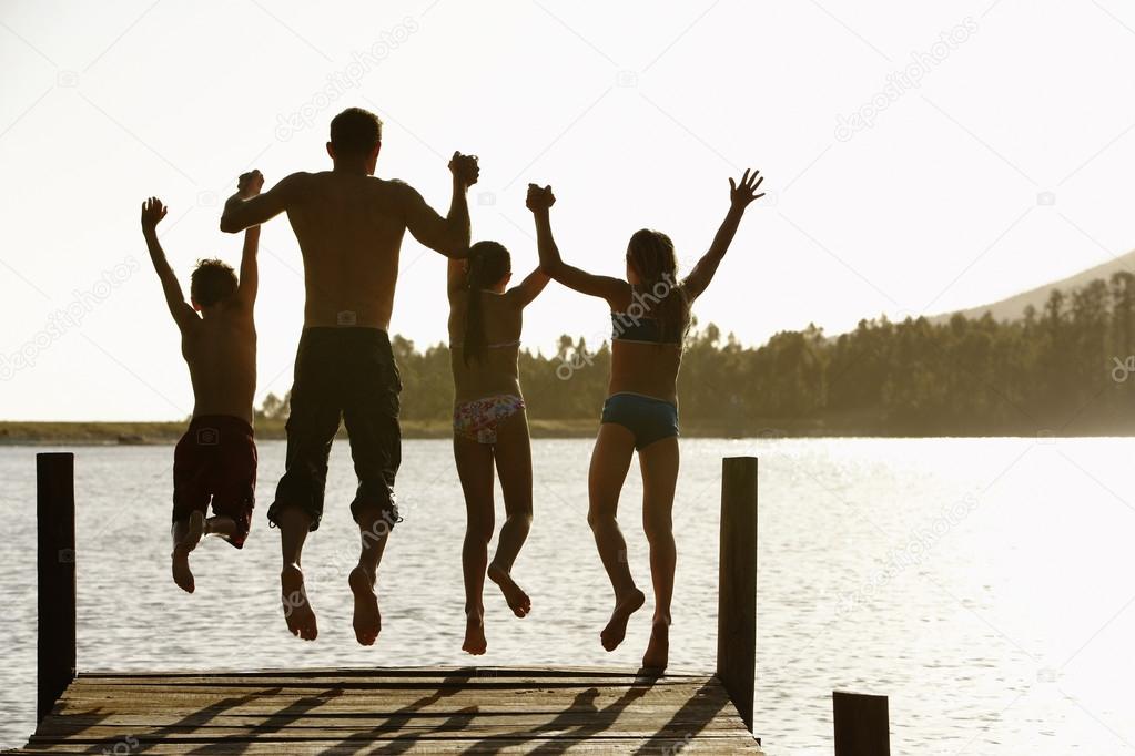 Father and children jumping off a pier