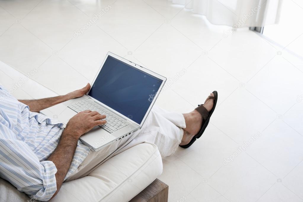 Man using laptop sitting on sofa