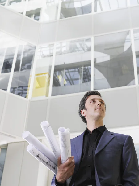 Hombre de negocios sosteniendo planos laminados —  Fotos de Stock