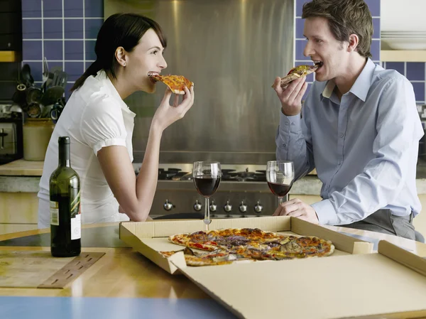 Casal comendo pizza na cozinha — Fotografia de Stock