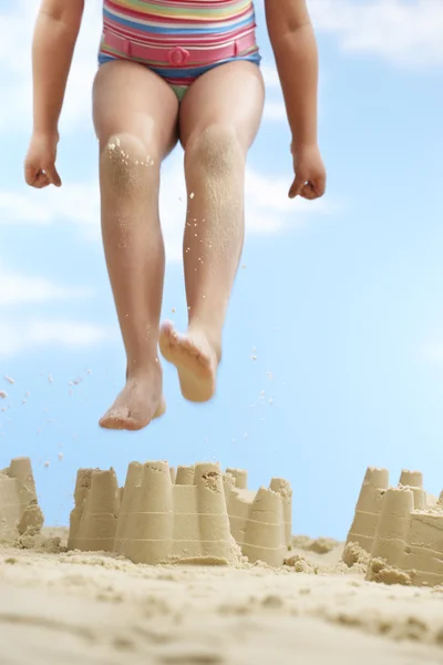 Girl  jumping on sand castle — Stock Photo, Image