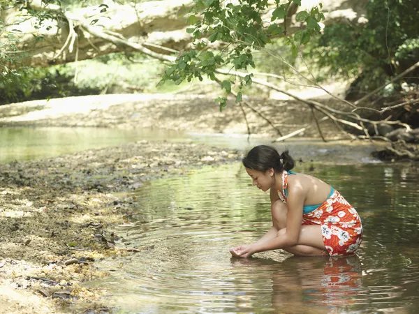 Woman squatting in lake — Stock Photo, Image