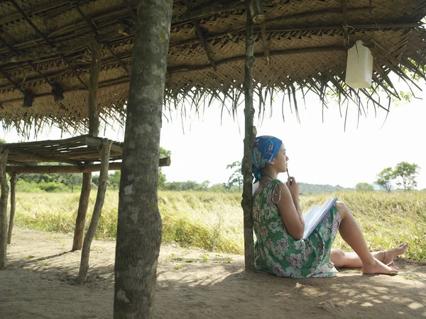 Mulher sentada à sombra da cabana — Fotografia de Stock