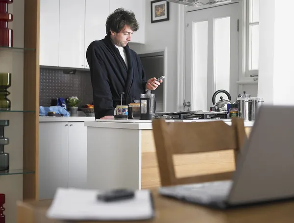 Mensajería de hombre con teléfono en la cocina —  Fotos de Stock