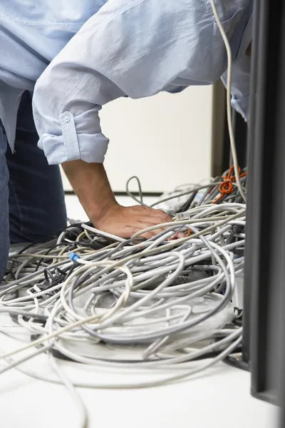 Uomo che lavora su groviglio di fili del computer — Foto Stock