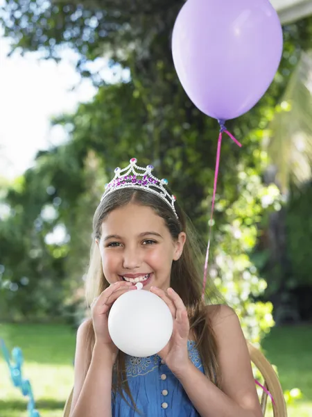 Girl blowing up balloons — Stock Photo, Image