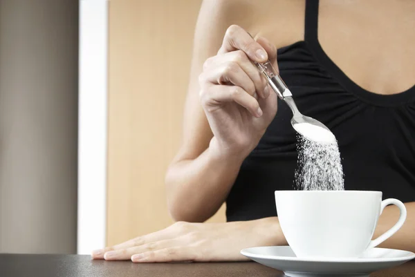 Woman pouring sugar into cup — Stock Photo, Image